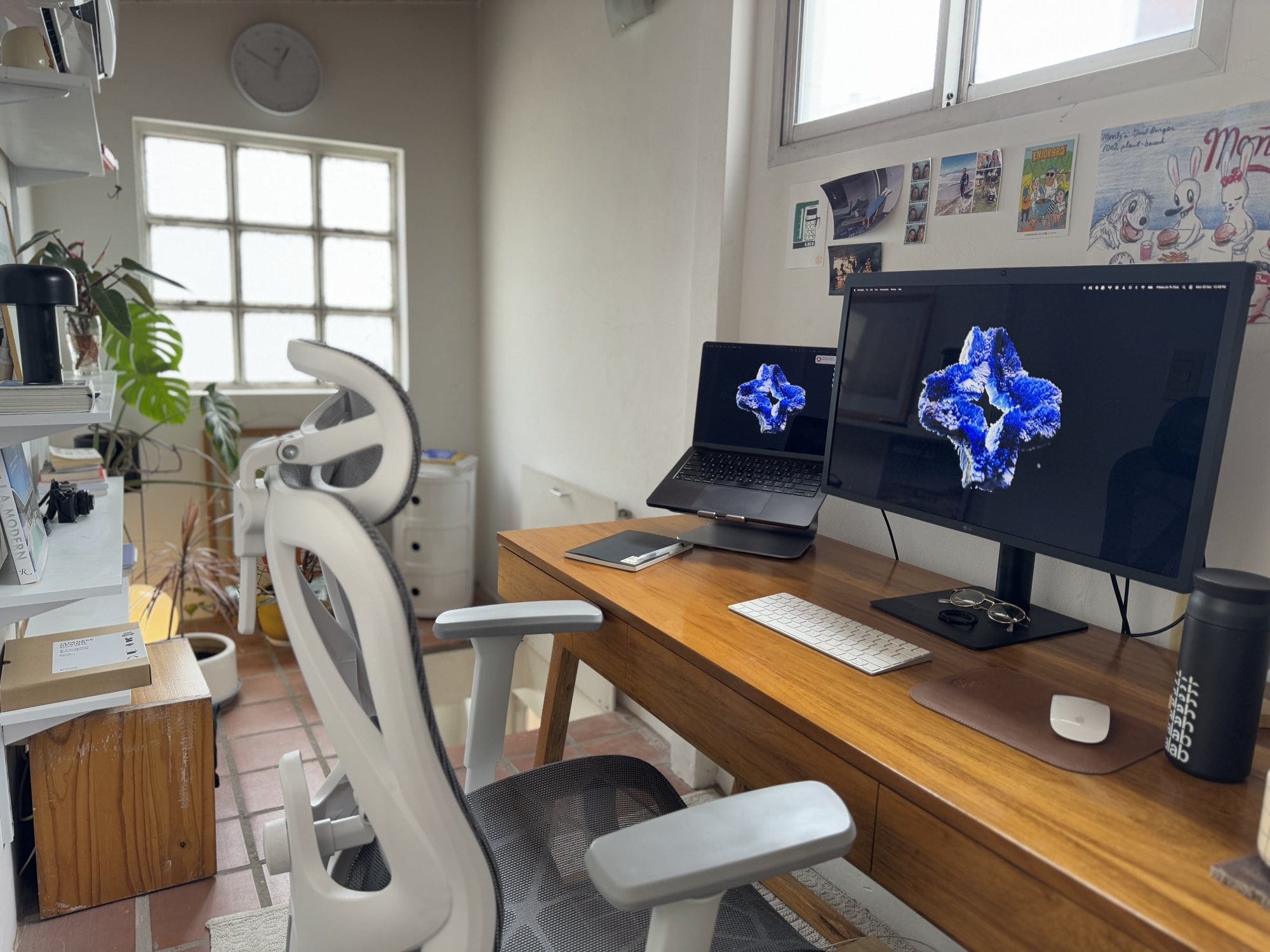 A small attic workspace with an Apple MacBook Pro M3 Pro on a Rain Design mStand360, an LG UltraFine 4K monitor, an Apple Keyboard, an Apple Magic Mouse, and an Actek Floe Plus EC727 chair