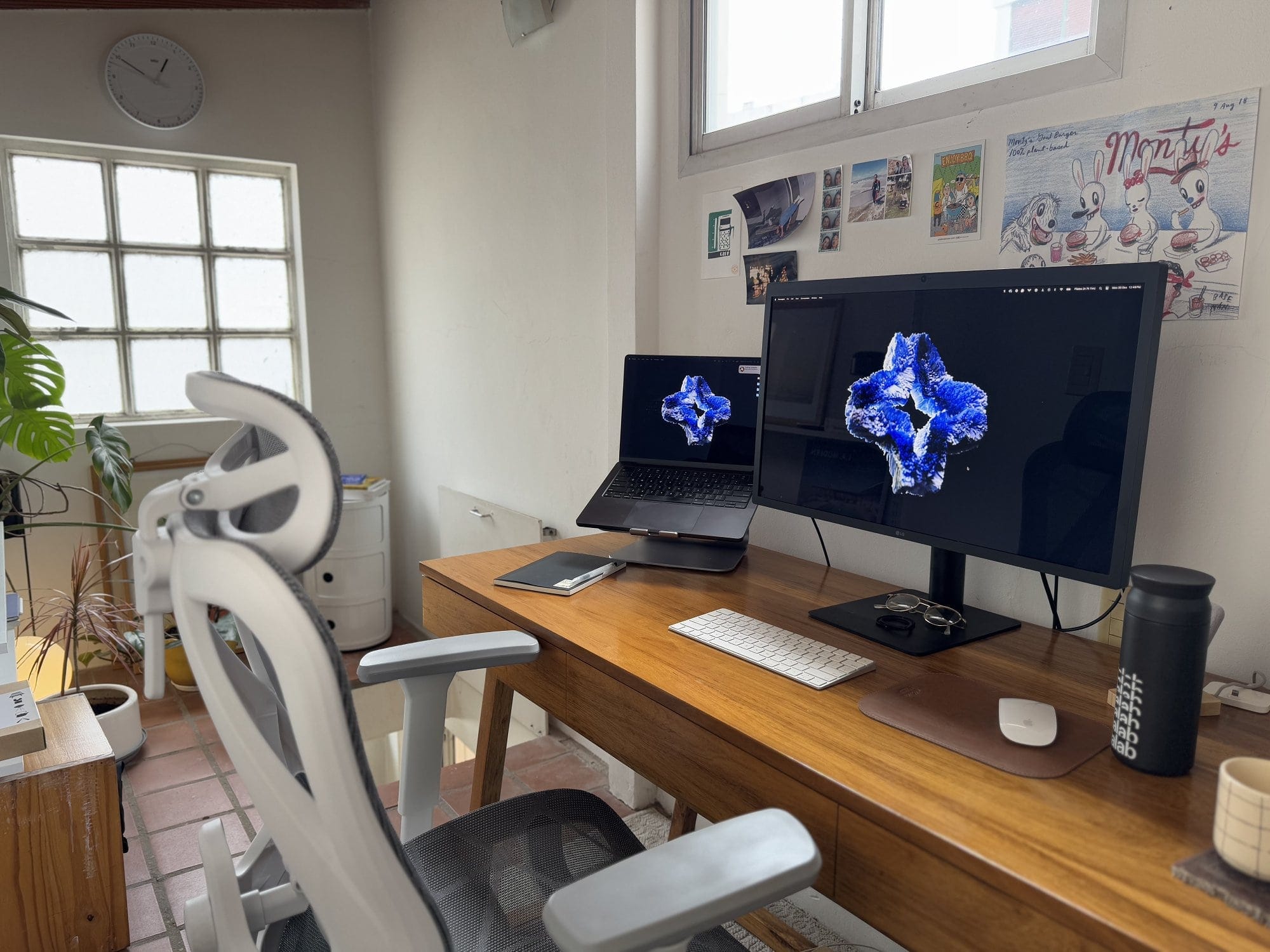 A home office with an Apple MacBook Pro M3 Pro on a Rain Design mStand360, an LG UltraFine 4K monitor, an Apple Keyboard, an Apple Magic Mouse, and an Actek Floe Plus EC727 chair