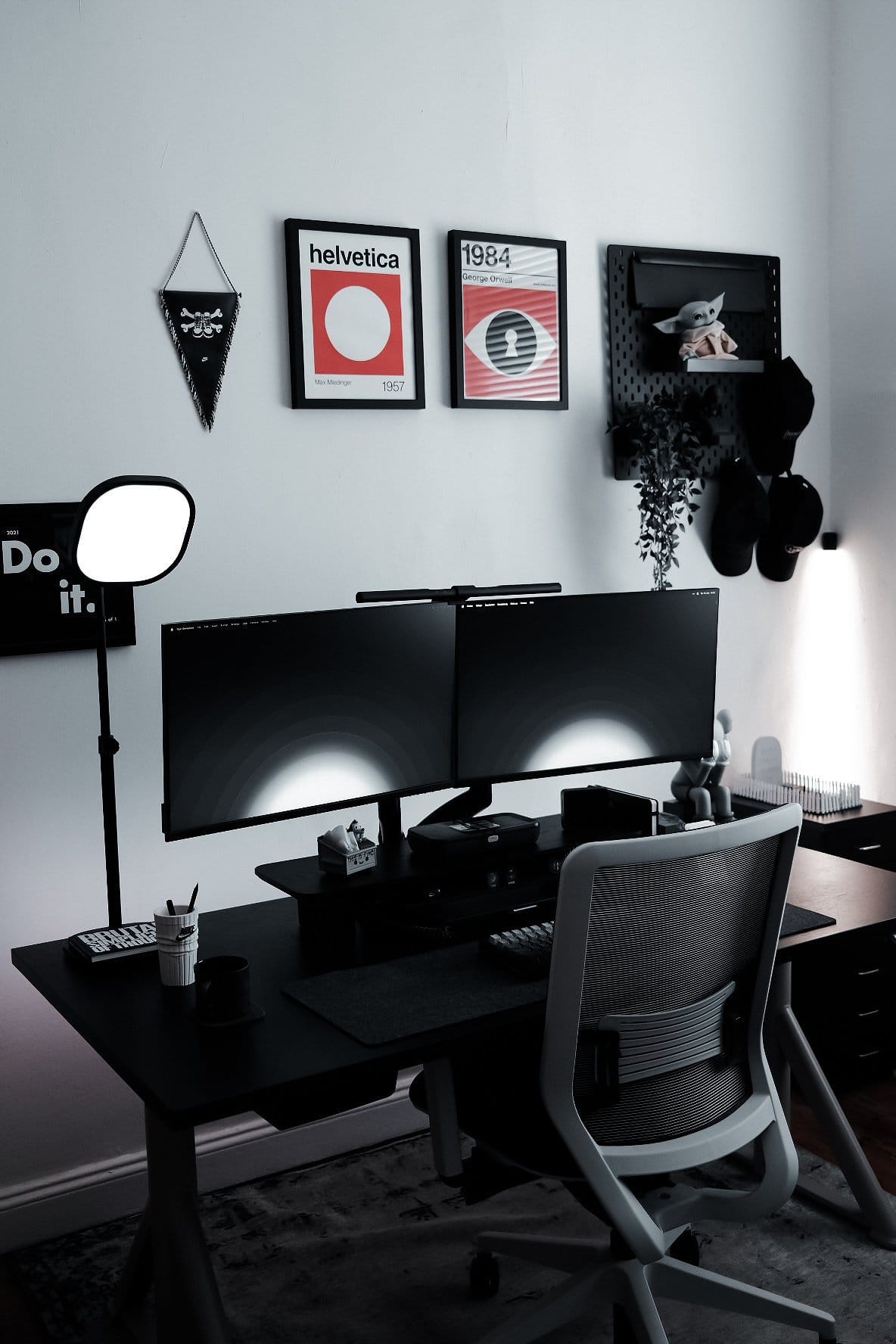 A dual Dell S2721QSA 27″ monitor setup with framed posters, a pegboard, and a Grogu figure on the wall