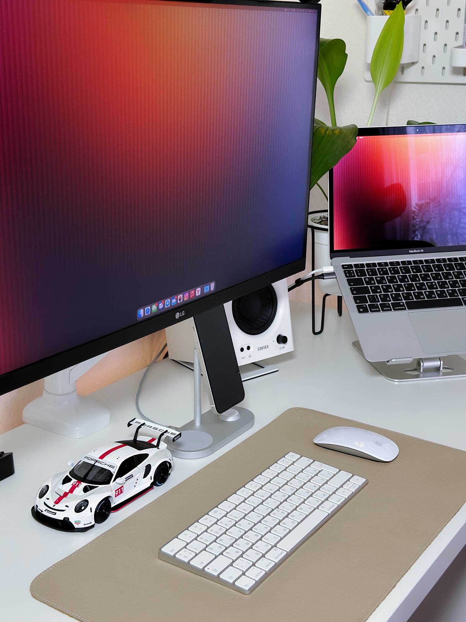 A WFH desk setup with an LG 27UL650-W monitor, a MacBook Air M1 2020 on an aluminium stand, Edifier MR4 speakers, an Apple Magic Keyboard 2 and Magic Mouse 2 on a Humanmotion desk mat, and a Porsche model car on the desk